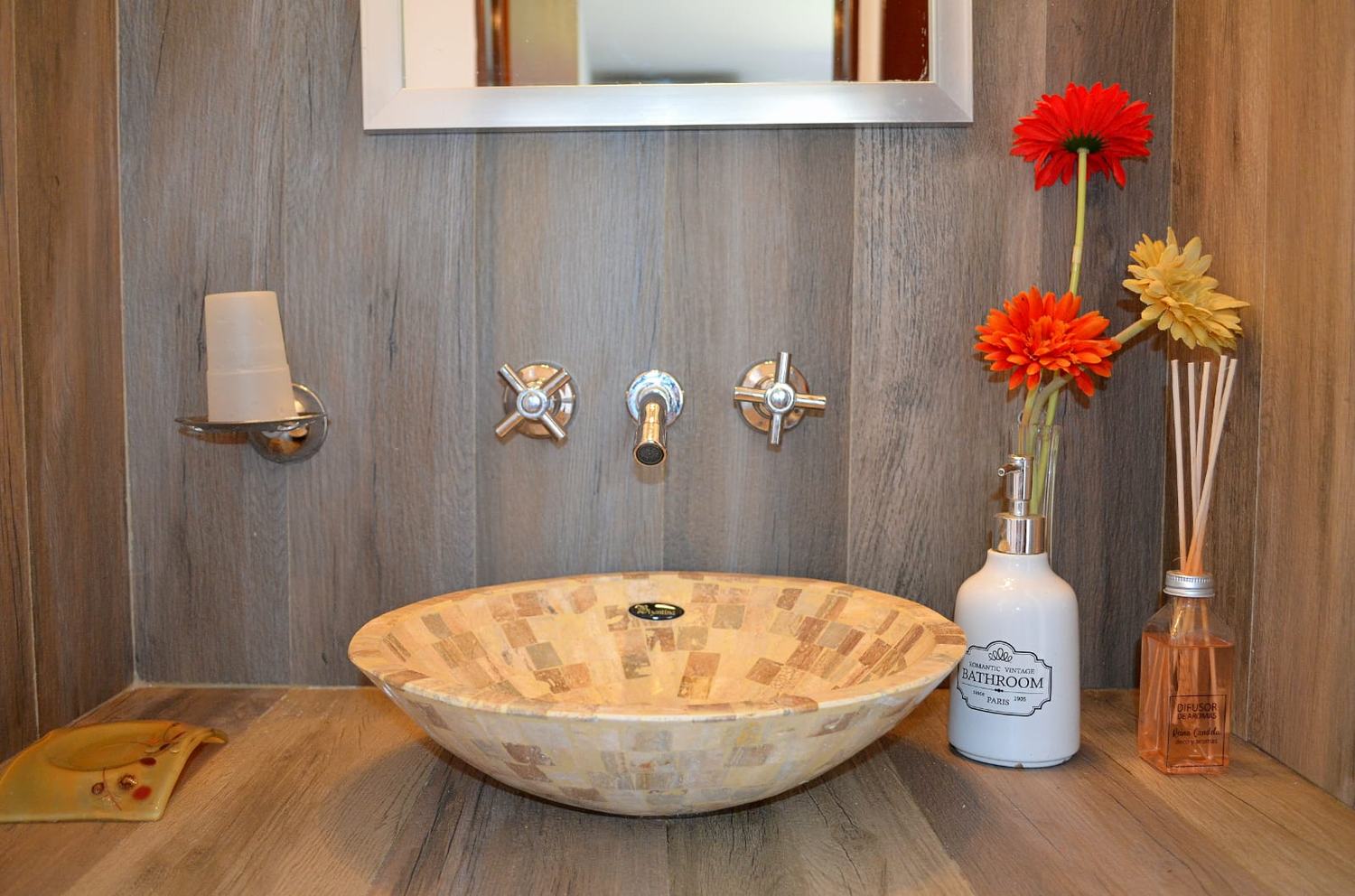 Baño con bacha de piedra sobre mueble de madera